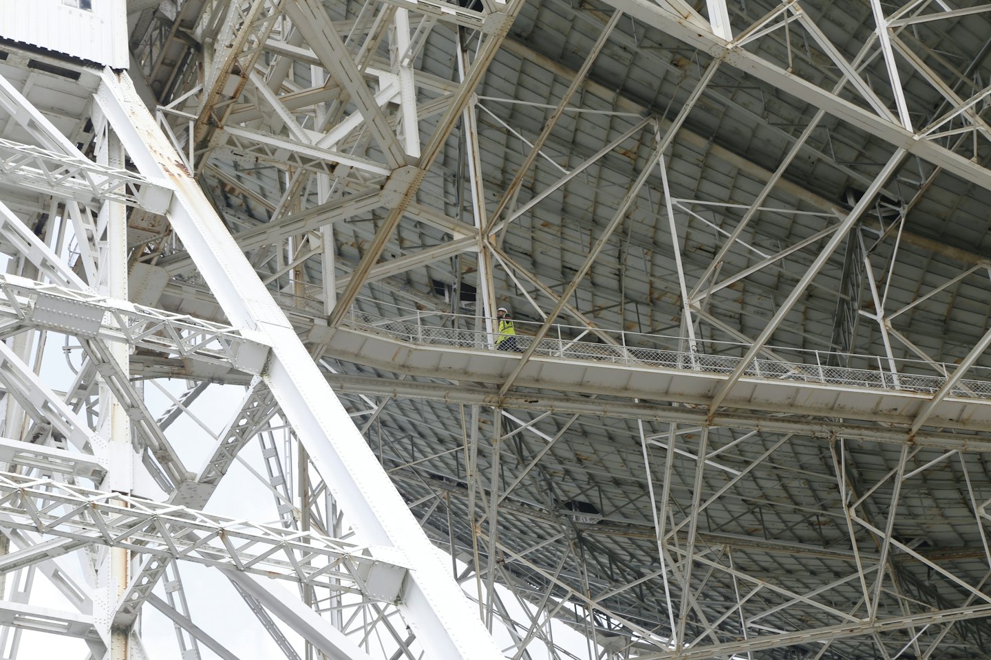 Operaio ispeziona un'intricata struttura metallica di un grande edificio.
