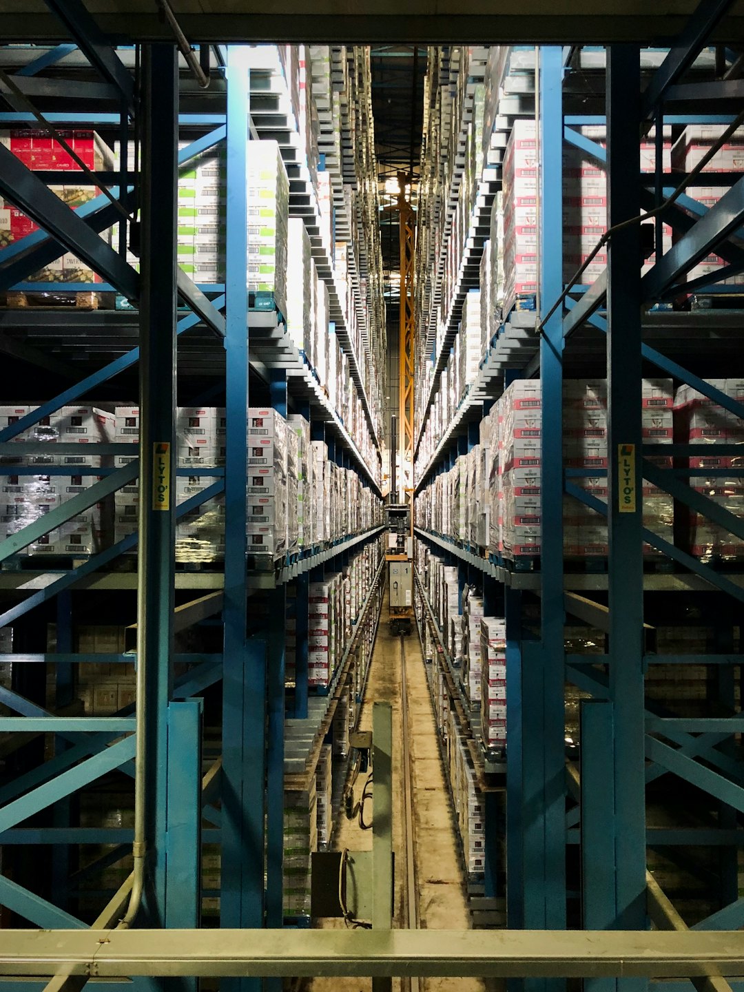 Corsia di magazzino automatizzato impilata con scatole e pallet.