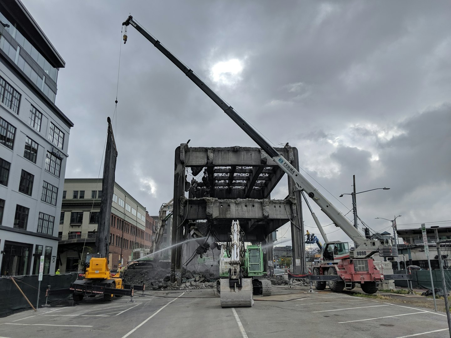 Un escavatore demolisce un edificio in cemento in un cantiere urbano.